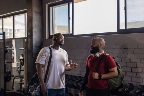 African men talking in urban gym after workout with duffel bag and headphones