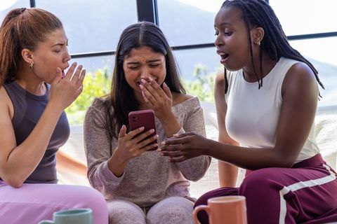 African american and diverse friends reacting to surprising smartphone text in loungewear