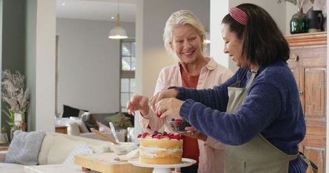 Diverse Women Friends Decorating Cake with Fresh Berries in Kitchen