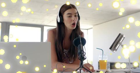 Female podcaster recording lively home studio session with headset microphone and laptop