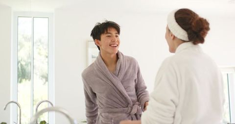 Couple sharing relaxed morning routine in bright minimalist bathroom wearing plush robes