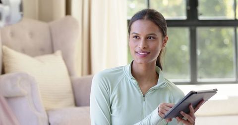 Serene african american woman holding tablet in sunlit cozy living room for remote work