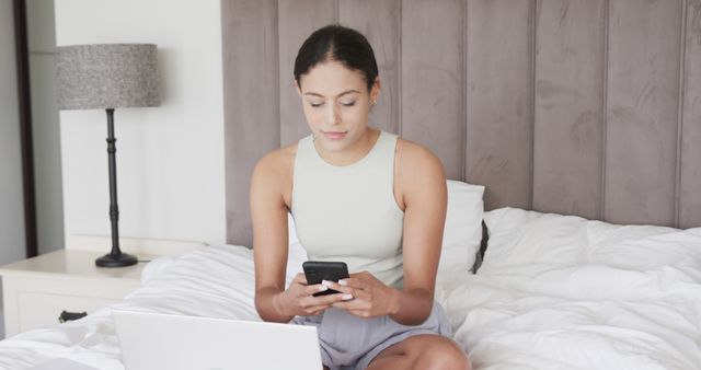 Woman Relaxing on Bed Using Smartphone with Laptop - Download Free Stock Images Pikwizard.com