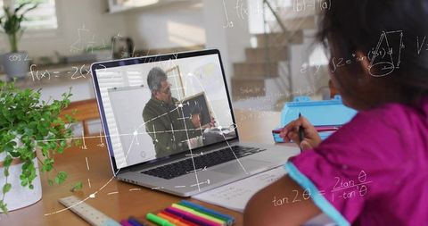 Young girl studying math with online tutor on laptop at wooden desk with bright markers