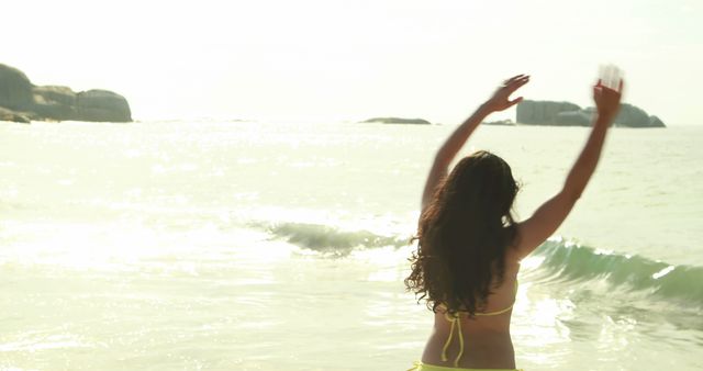 Woman Enjoying at Beach with Arms Raised in Bright Sunlight - Download Free Stock Images Pikwizard.com