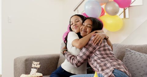 Two Teen Girls Embracing at Balloons and Birthday Cake Celebration