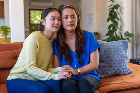 Asian mother and daughter connecting at home on cozy sofa