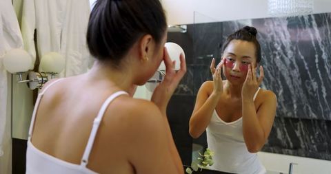 young woman applying rejuvenating under-eye gel patches in bathroom - Download Free Stock Images Pikwizard.com