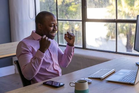Smiling Man Celebrating Success at Office Desk
