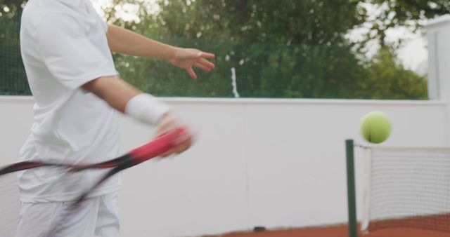 Midsection of caucasian male tennis player returning ball, playing on an outdoor tennis court. Sport, competition, fitness and healthy active lifestyle.