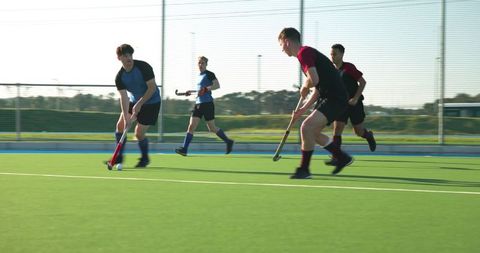Young Athletes Playing Field Hockey on Green Turf