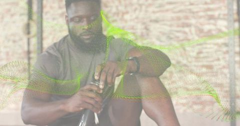 Man opening shaker bottle after workout in industrial gym with green digital wave overlay