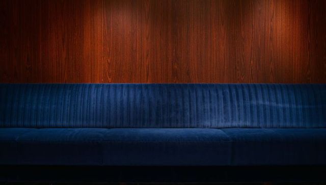 Indigo velvet banquette with channel tufting against warm wood panel wall