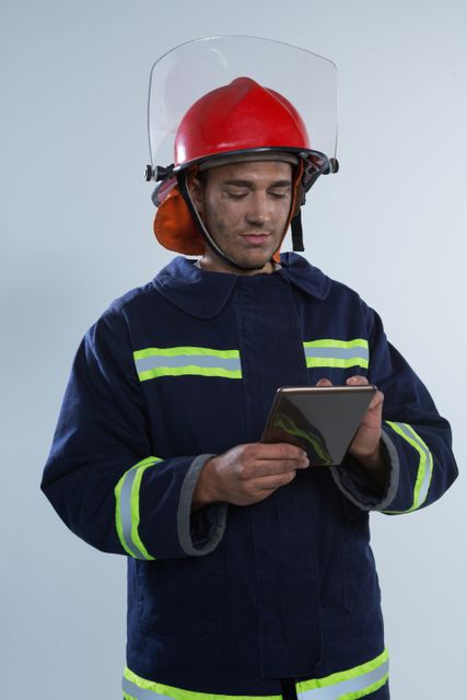 Smiling fireman using digital tablet against white background