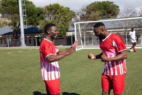 Energetic soccer teammates celebrating victory on field