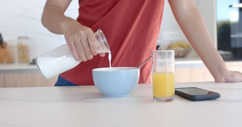 Young Man Preparing Breakfast with Milk and Juice in Modern Kitchen