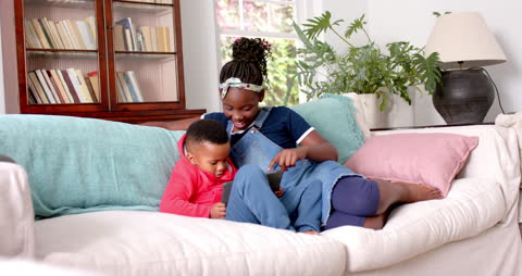 Brothers and Sisters Bonding on Sofa Using Tablet Device