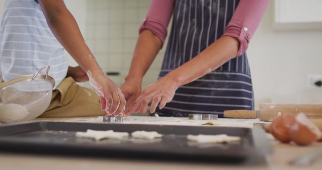A family baking together in the kitchen, rolling out dough and using cookie cutters. Ideal for showcasing family bonding activities, cooking classes, and home baking recipes. This can be used in advertisements or blogs related to family life, parenting tips, and homemade baking.