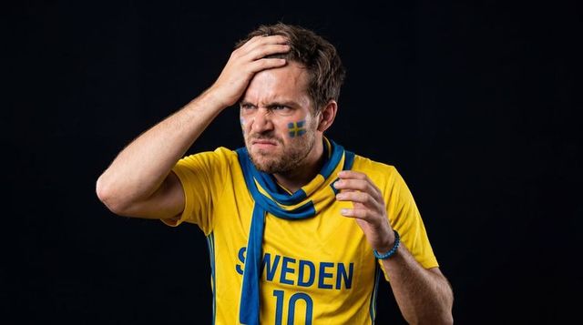 Grimacing sweden football fan holding head wearing sweden 10 jersey and blue scarf