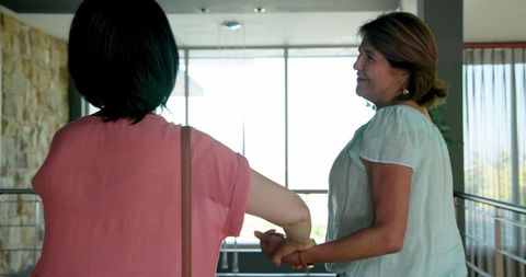 Senior Multiracial Friends Greeting with Embrace by Doorway