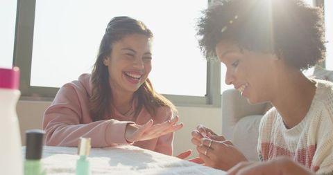 Sunlit home manicure session featuring diverse friends laughing and sharing nail care