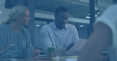Mid-adult man reading documents during collaborative meeting in modern office boardroom