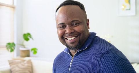 Smiling african american man relaxing on sofa in cozy bright living room