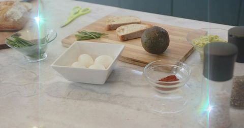 Bright morning breakfast prep on marble counter with eggs, avocado and bread