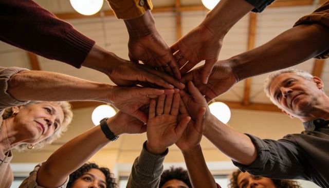 Intergenerational community hands joining in circle for teamwork, unity and support