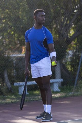 African american tennis player preparing serve on outdoor hardcourt showing focus