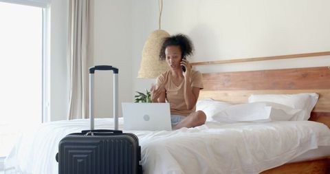 Traveler Using Laptop in Cozy Hotel Room With Suitcase