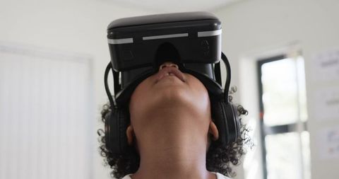 Teen exploring virtual reality with vr headset and headphones tilting head upward