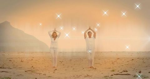 Sunrise Beach Yoga Duo Wearing White Outfits Practicing Meditation with Sparkling Glow