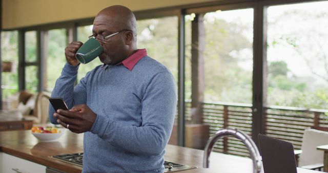 African American Man Drinking Coffee and Checking Smartphone in Modern Kitchen - Download Free Stock Images Pikwizard.com