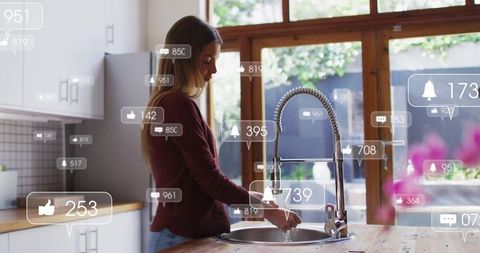 Woman in Modern Kitchen Engaging with Social Media Icons