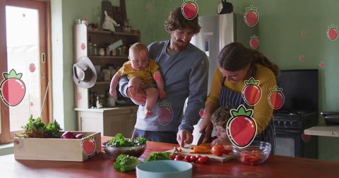 Caucasian family of three engaging in cooking activity in a cozy kitchen. Strawberry icons interposed in image add a digital, playful touch, blending everyday life with modern technology flair. Mom slicing vegetables accompanied by father holding baby while younger child participates with cutting board. Represents healthy home-cooked meals and family togetherness. Ideal for ads promoting kitchen products, family nutrition tutorials, integrating children into cooking activities or showcasing technology in family settings. Highlights themes of family life, active parenting, using mixed media storytelling.