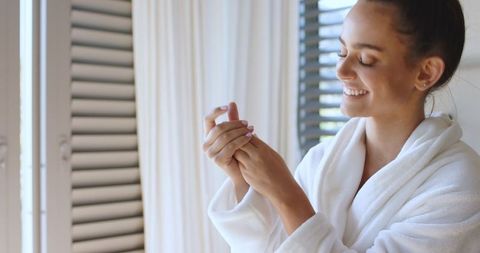 Woman in Luxury Bathrobe Relaxing by Sunlit Window