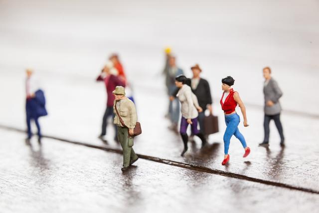 This conceptual image features miniature figurines representing diverse commuters traveling. Ideal for presentations, articles, or advertising campaigns related to travel, urban life, and human movement. Useful for illustrating concepts of diversity, daily commute, and journeys.