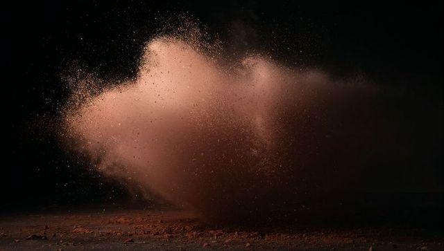 Dynamic burst of reddish-brown dust against dark background