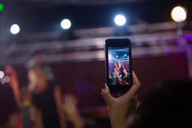 Audience recording video of band on mobile phone in nightclub