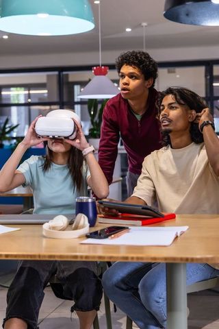 Team exploring virtual reality app at coworking table, young professionals testing