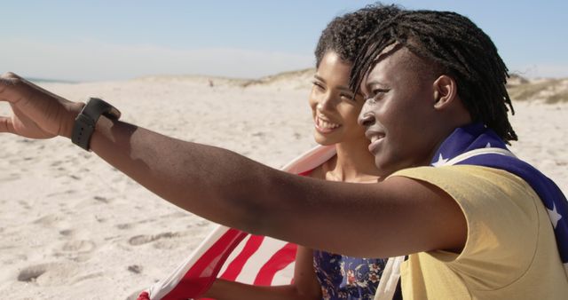 Young African American couple smiling on beach looking at horizon wrapped in American flag - Download Free Stock Images Pikwizard.com