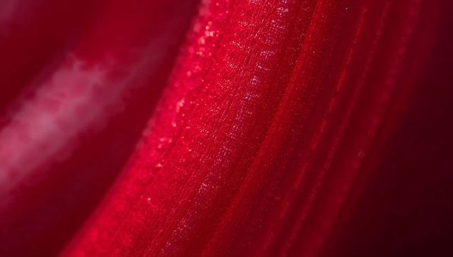 Macro shot of vibrant red petal with glistening details and texture