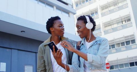 Joyful African American Twin Sisters Sharing Music on City Street