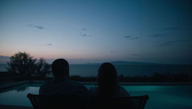 Silhouetted couple watching twilight over pool and ocean from terrace