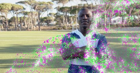 Confident soccer player standing on turf with dynamic magenta-green particle trail effect
