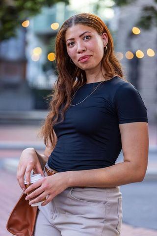 Confident african american woman standing at dusk holding coffee cup and leather bag urban fashion