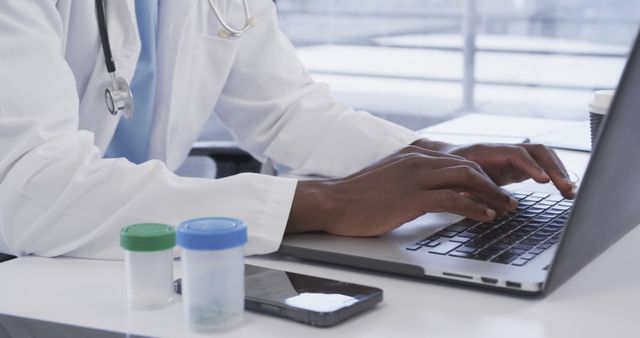 Doctor Typing on Laptop in Office with Medical Tools Nearby - Download Free Stock Images Pikwizard.com