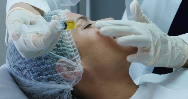 A woman is receiving a cosmetic injection in a beauty clinic. This image can be used for topics related to beauty treatments, medical skincare, anti-aging procedures, and health care services.