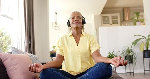 Senior African American Woman Meditating with Headphones at Home